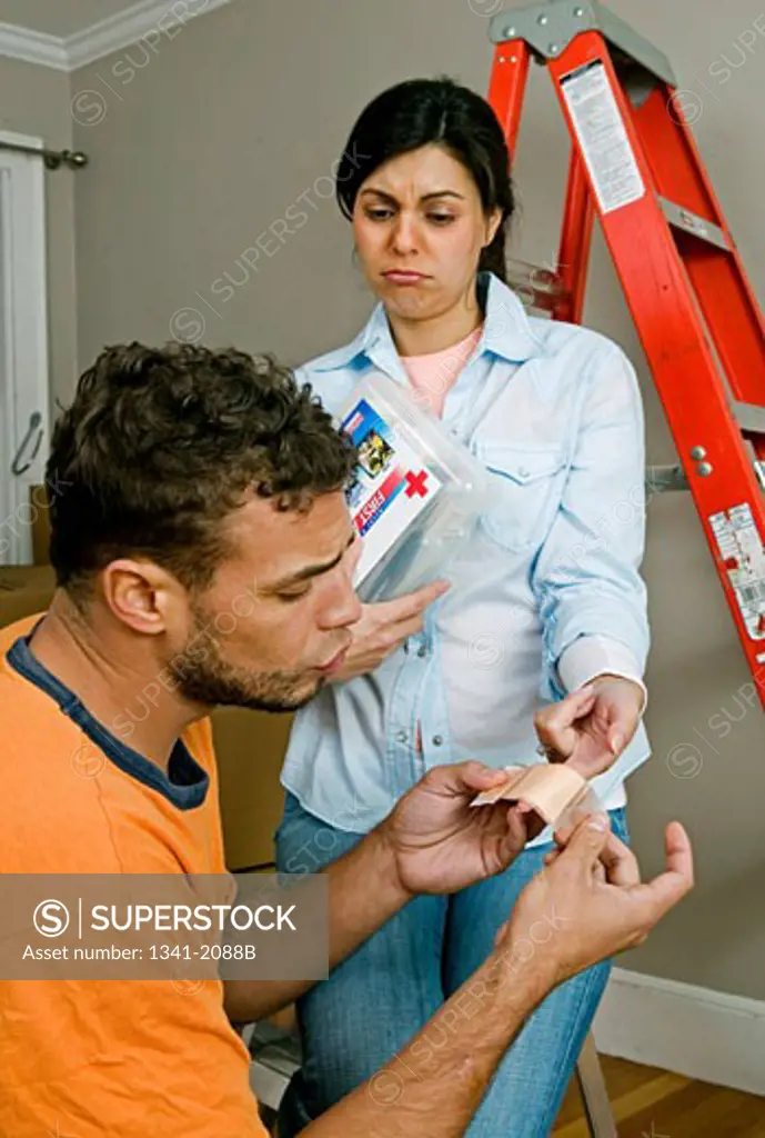 Young man putting a bandage on a young woman's finger