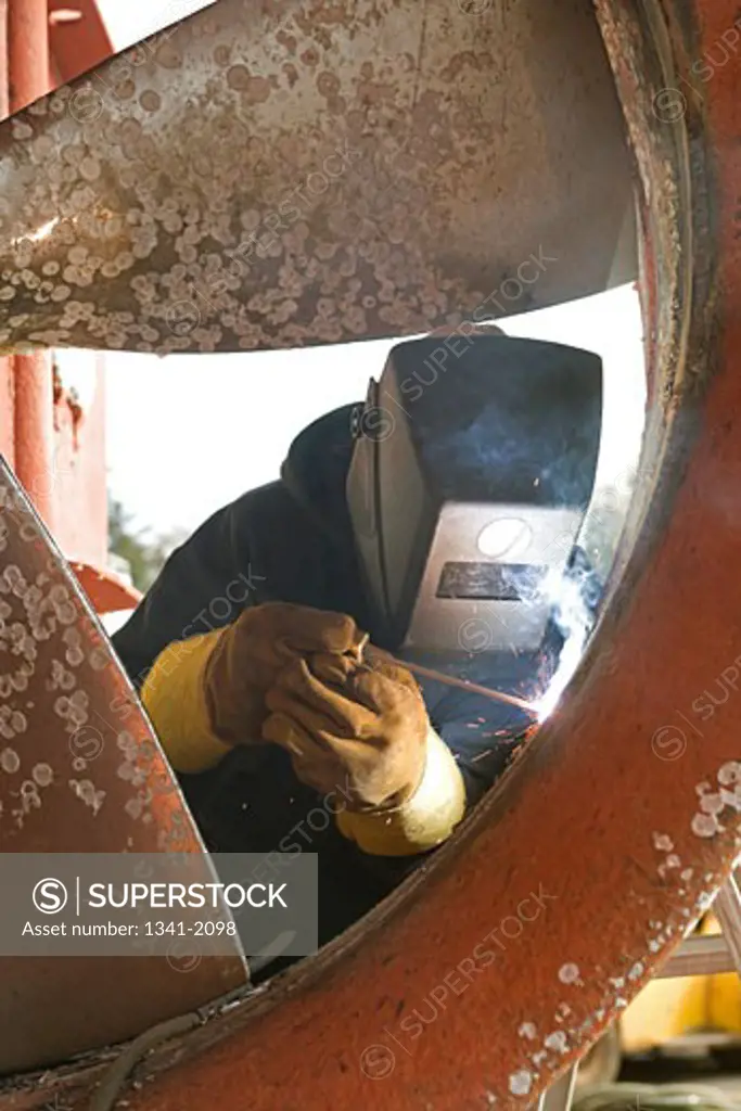 Welder welding a propeller in a shipyard