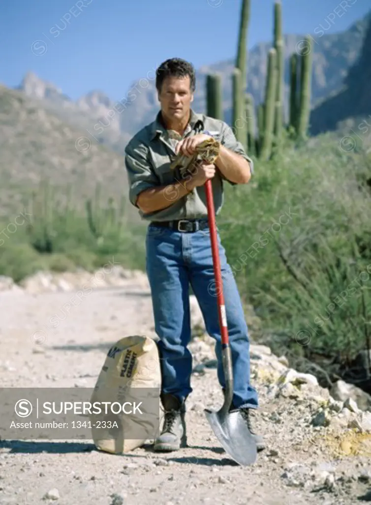 Portrait of a construction worker standing with a shovel and a sack