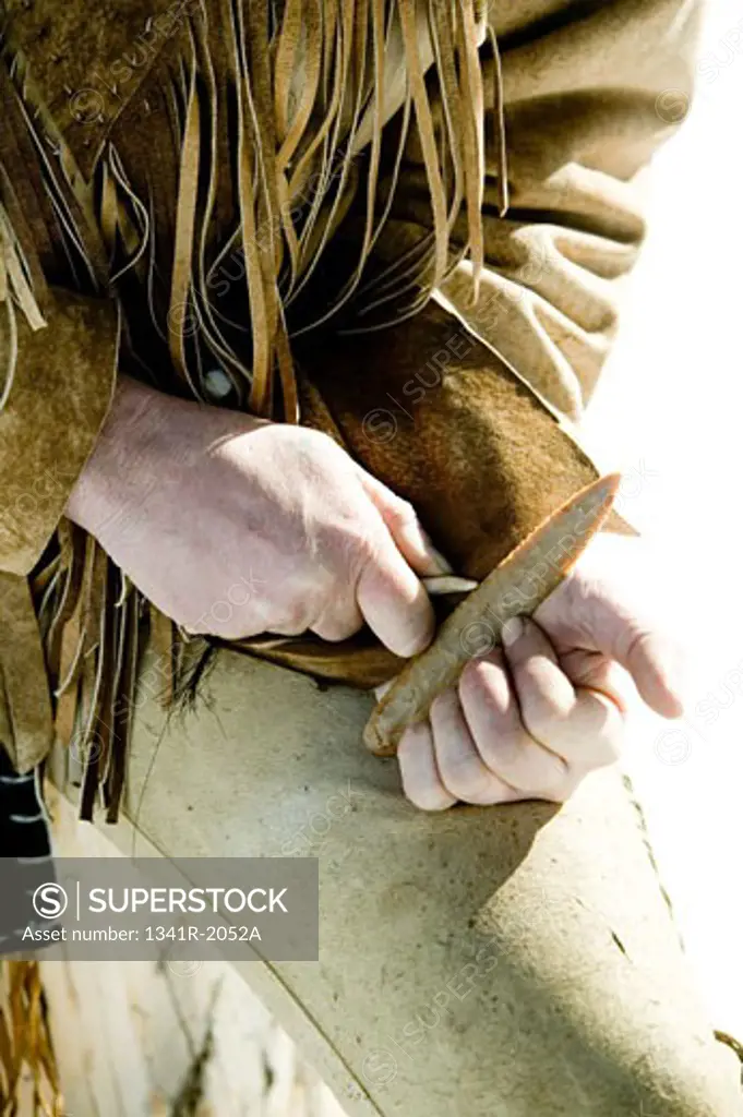 Close-up of a hunter's hand knapping a piece of stone using an obsidian stone, Jackson, Wyoming, USA