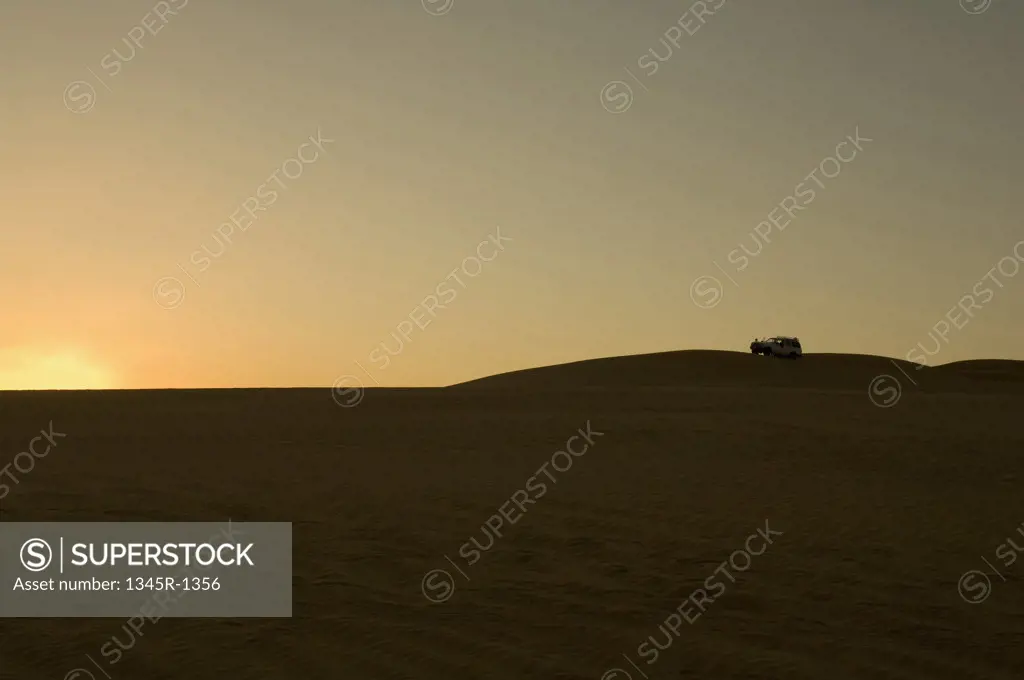 Silhouette of a 4x4 vehicle in a desert at sunset, Erg Awbari, Fezzan, Libya