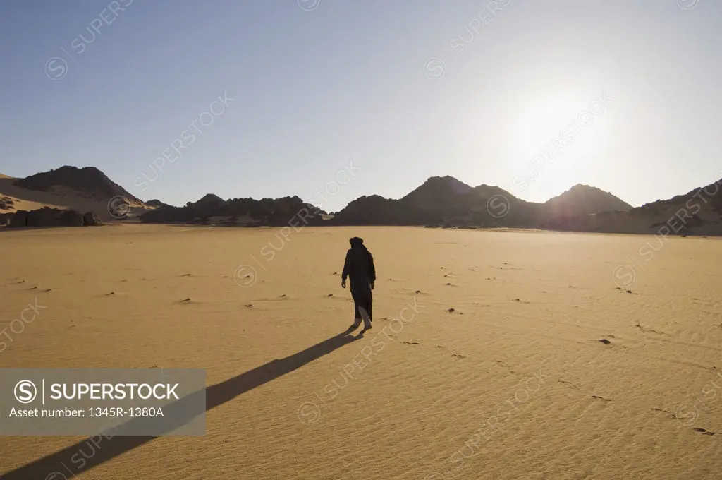 Tuareg man walking in a desert, Tadrart Acacus, Fezzan, Libya