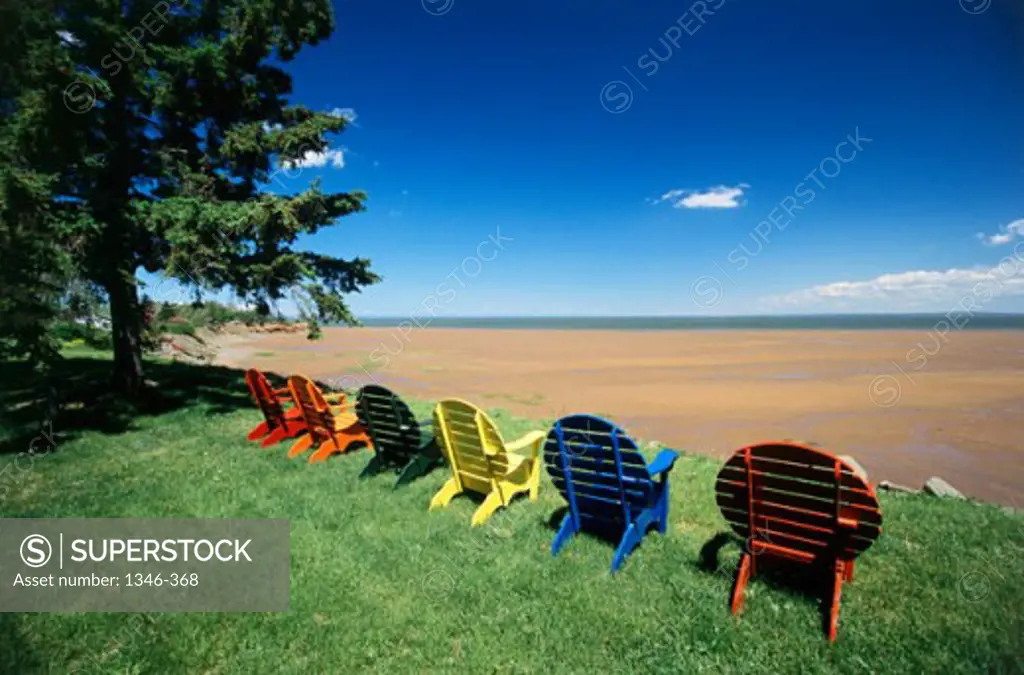 Row of empty adirondack chairs on the grass, Minas Basin, Nova Scotia, Canada
