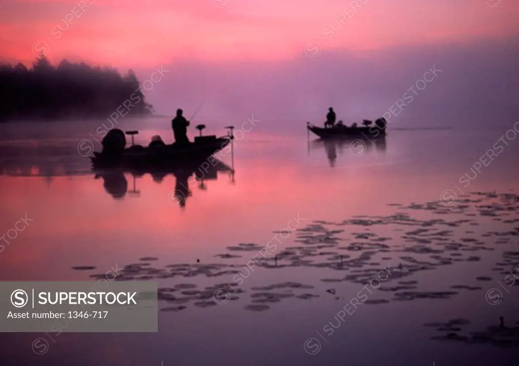 Silhouette of two people fishing in a lake