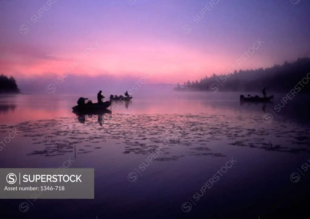 Silhouette of three people fishing in a lake