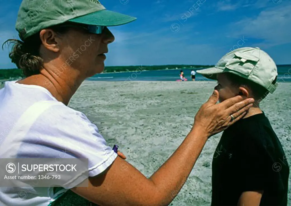 Senior woman applying suntan lotion to her grandson's face