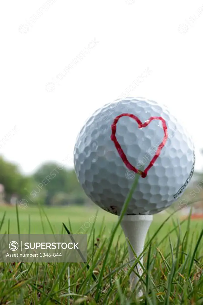 Close-up of a golf ball on a tee with a heart shape drawn on it