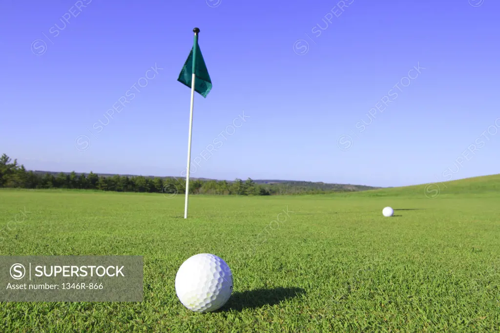 Golf flag with two golf balls in a golf course