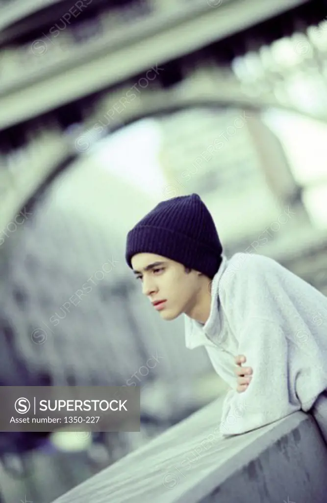 Side profile of a teenage boy leaning on a wall