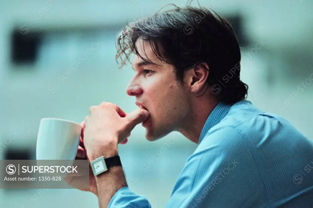 Side profile of a young man holding a coffee cup