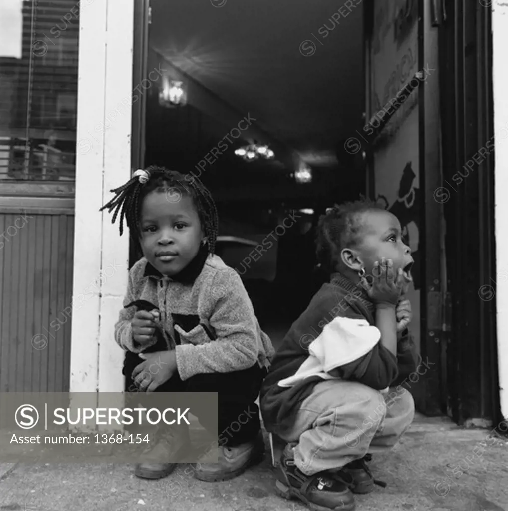 Two sisters sitting and waiting in a doorway