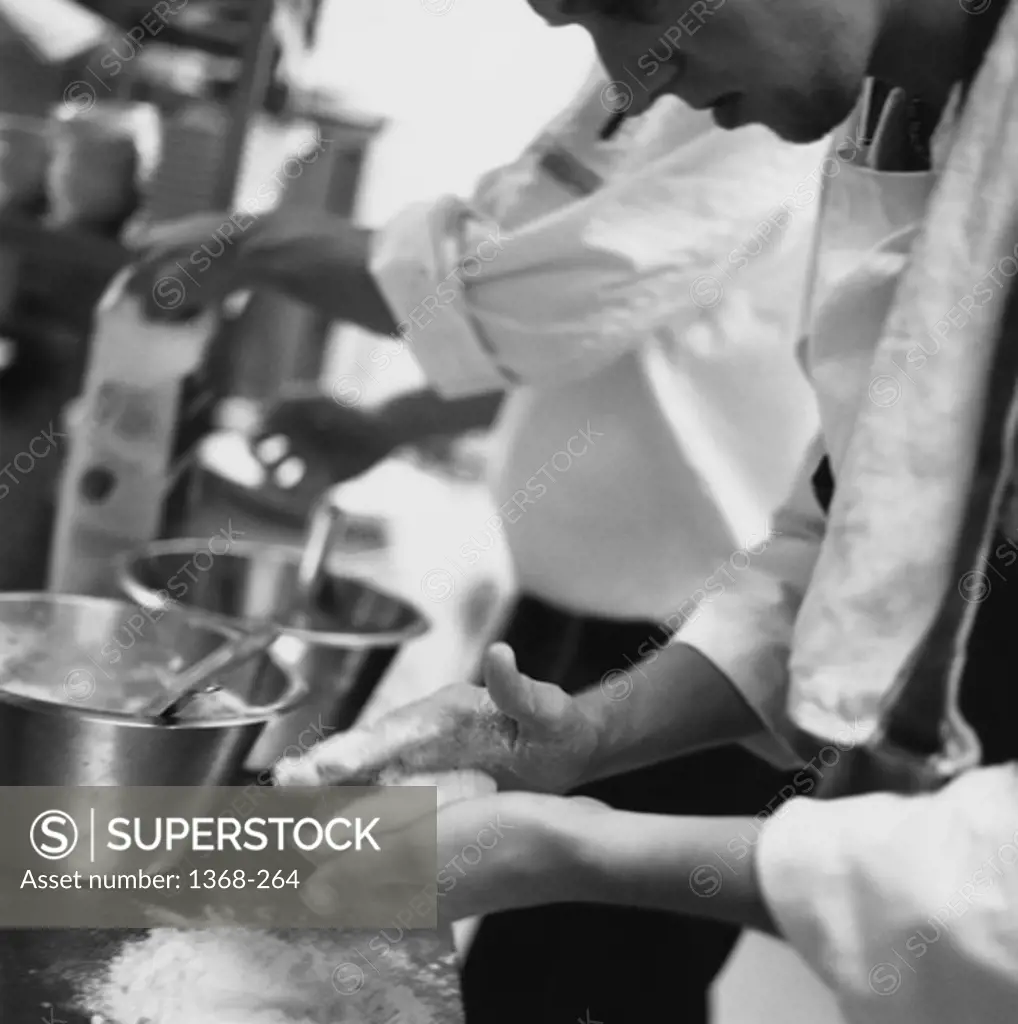 Side profile of two chefs preparing food in a kitchen