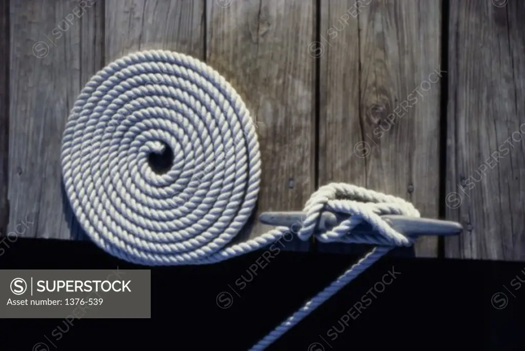 High angle view of a coiled rope tied to a cleat on a dock