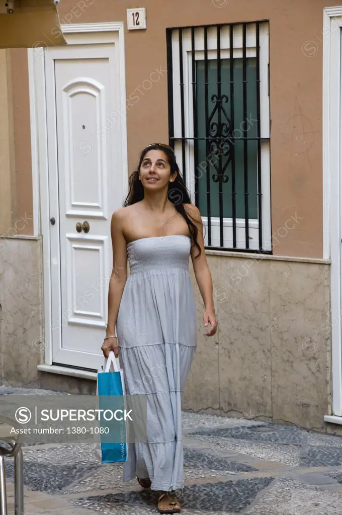Woman carrying a shopping bag in a street, Malaga, Andalusia, Spain