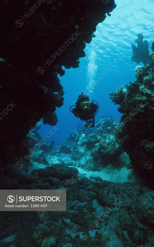 Scuba diver between the rocks underwater, Cayman Islands