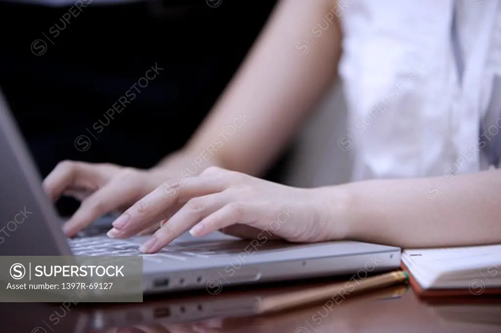 Close-up of young woman's hands using laptop