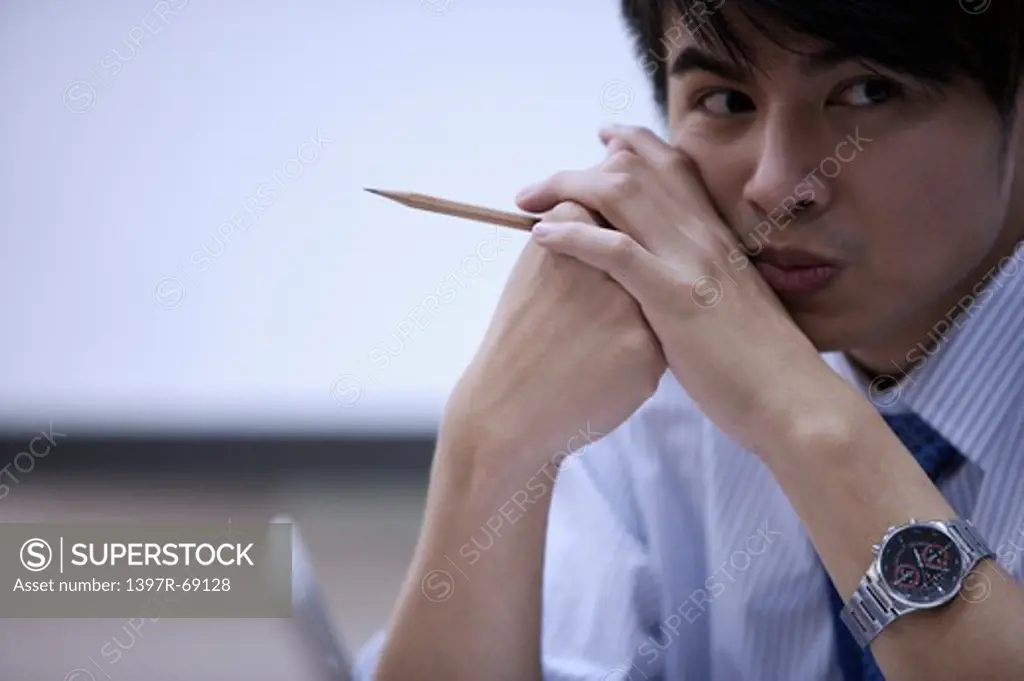 Young man holding a pencil and looking away