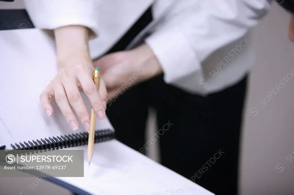 Close-up of young woman's hand pointing with a pencil