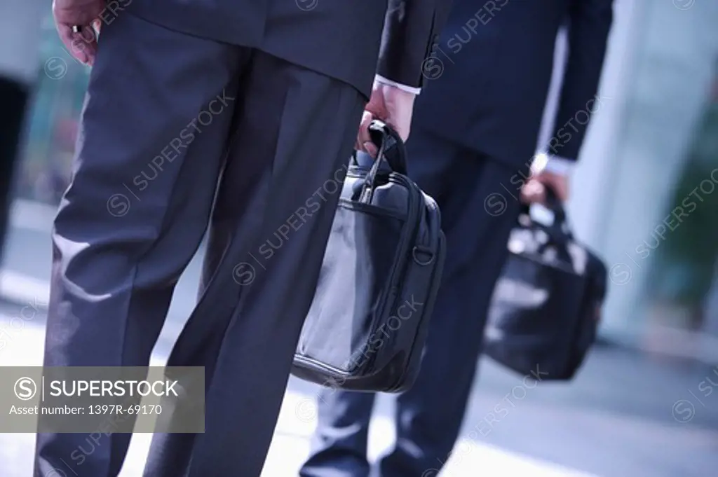 Two businessmen well-dressed standing and holding briefcase