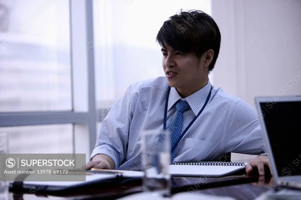 Young man sitting and looking away with smile in office