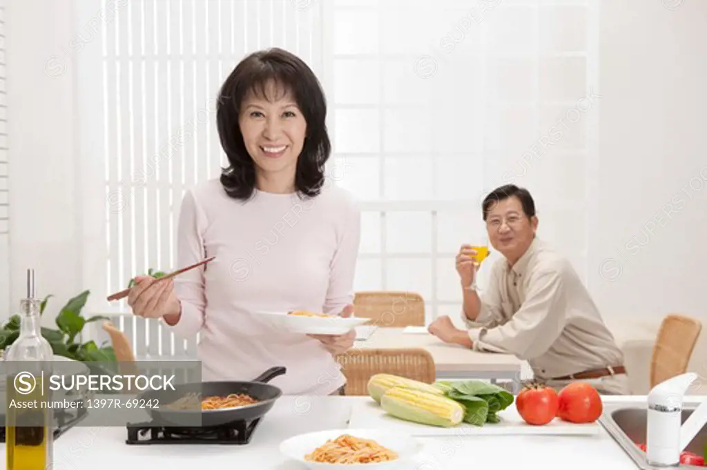 Couple, Wife cooking food and husband drinking near the table with smile