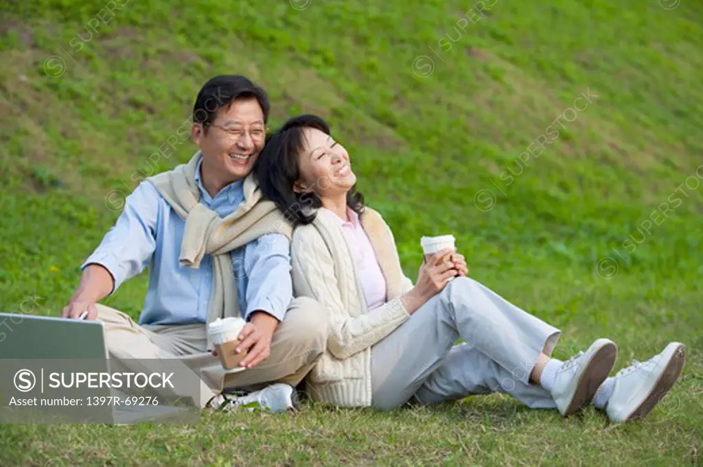 Couple, Couple sitting on the lawn with back to back and smiling happily