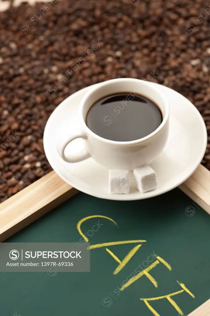 Coffee, Close-up of a cup of coffee above a stack of coffee beans