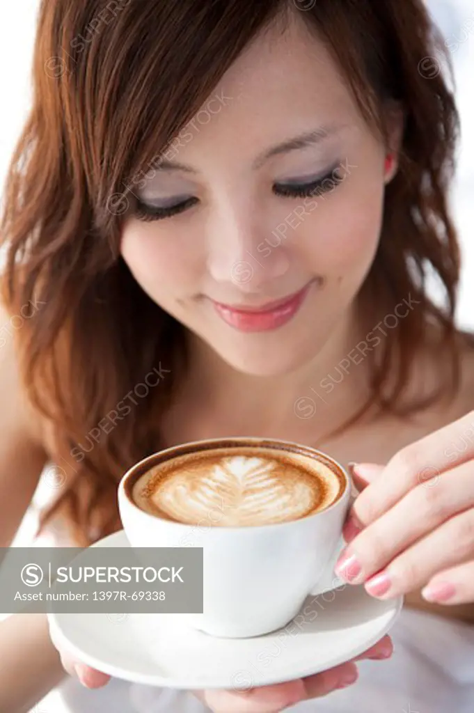 Coffee Break, Young woman holding a cup of cappuccino and looking down with smile