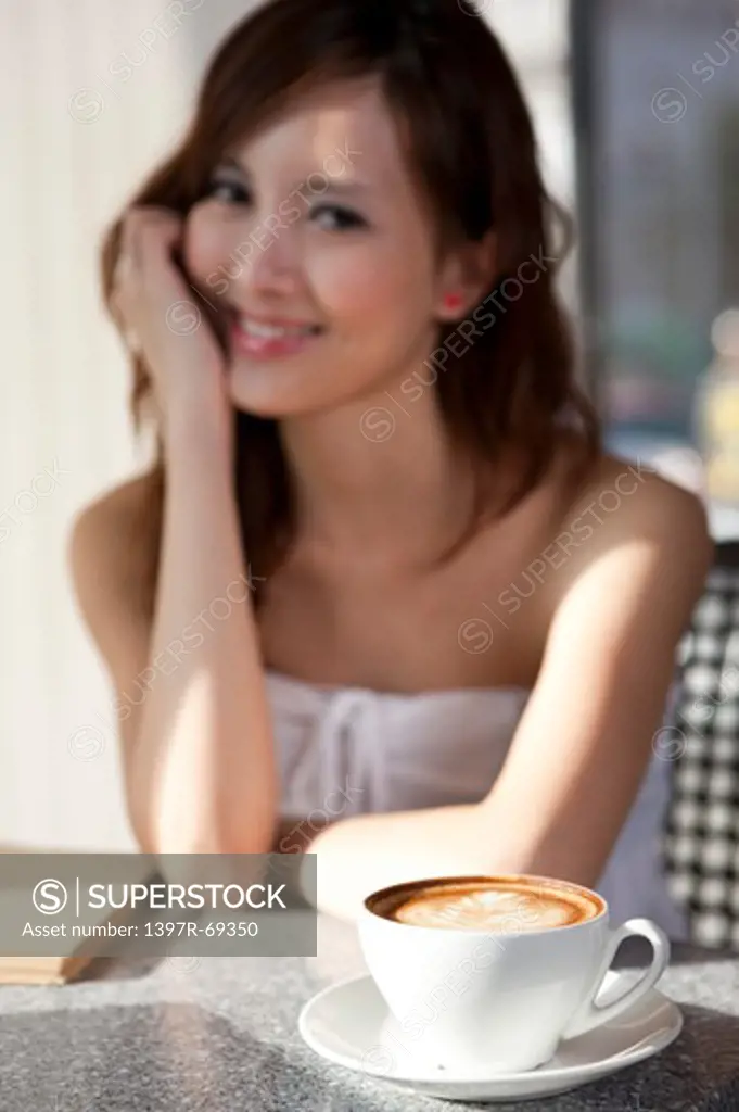 Coffee Break, Young woman sitting with a cup of coffee and looking at the camera with smile
