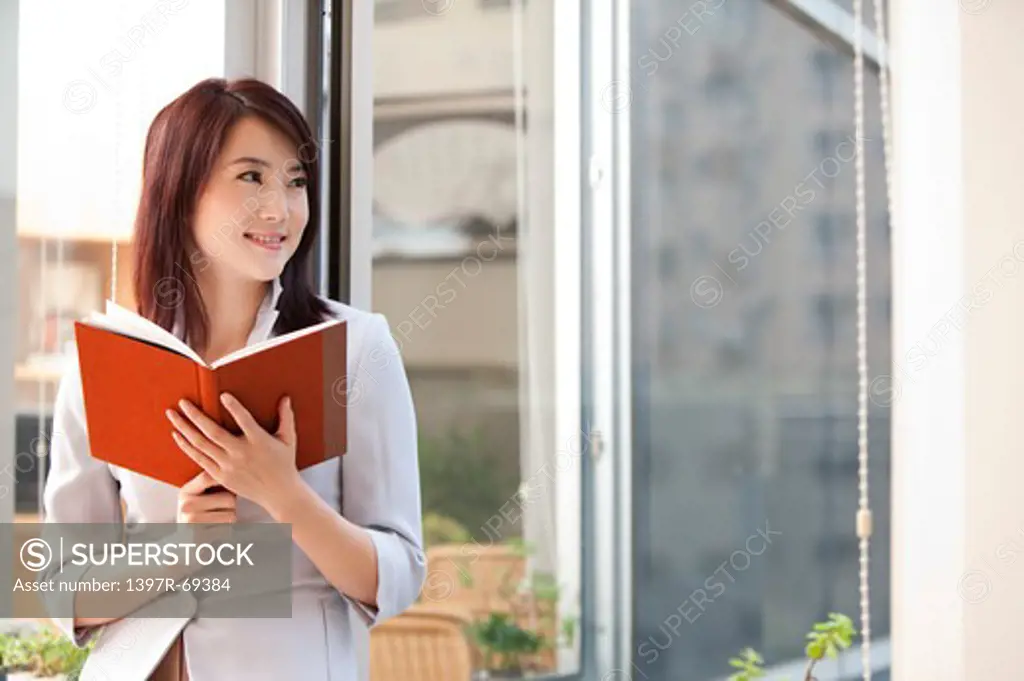 Woman holding a book and looking away with smile