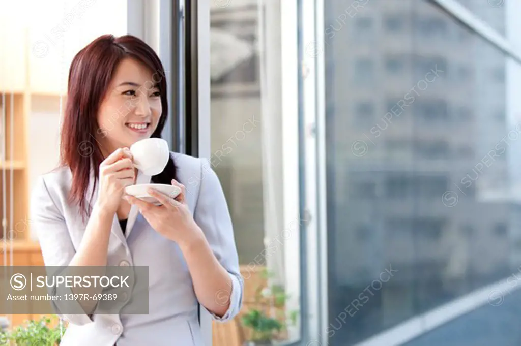 Woman holding a cup of coffee and looking away with smile