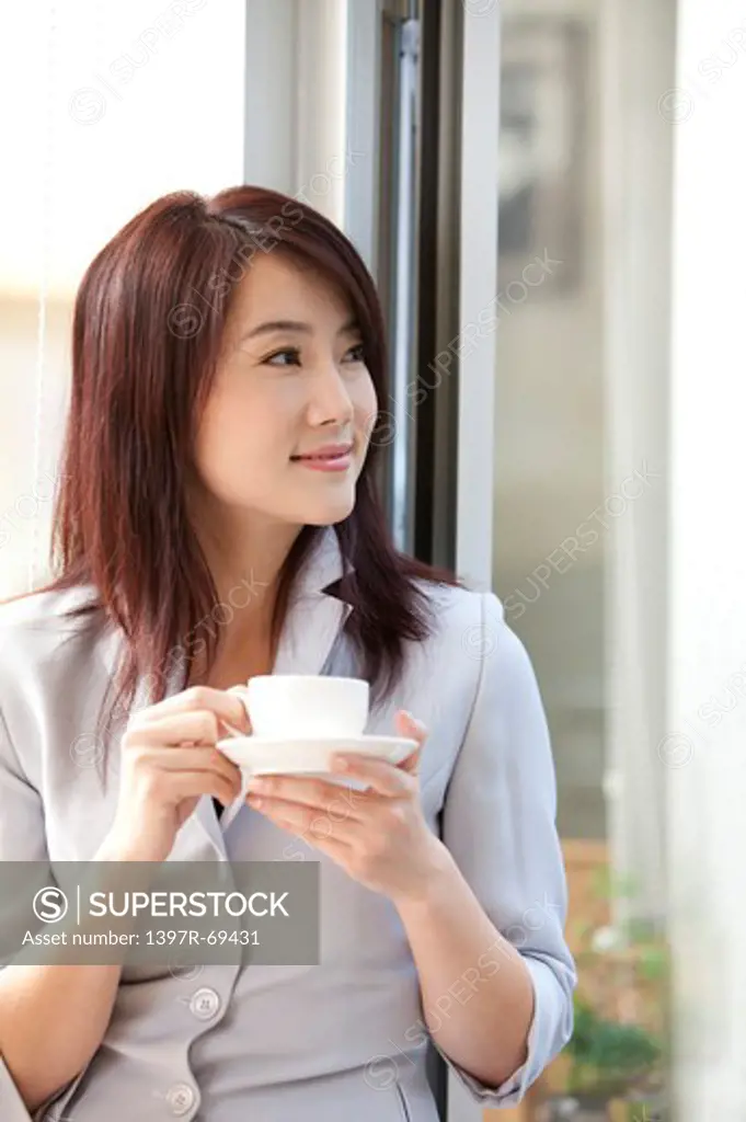 Woman holding a coffee cup and looking away with smile
