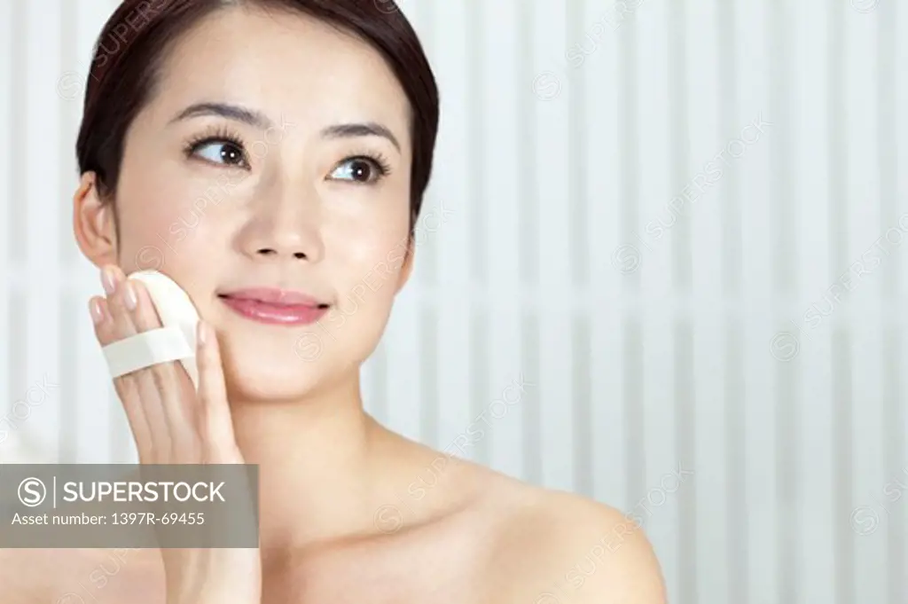 Beauty Treatment, Woman looking away and holding powder puff on face