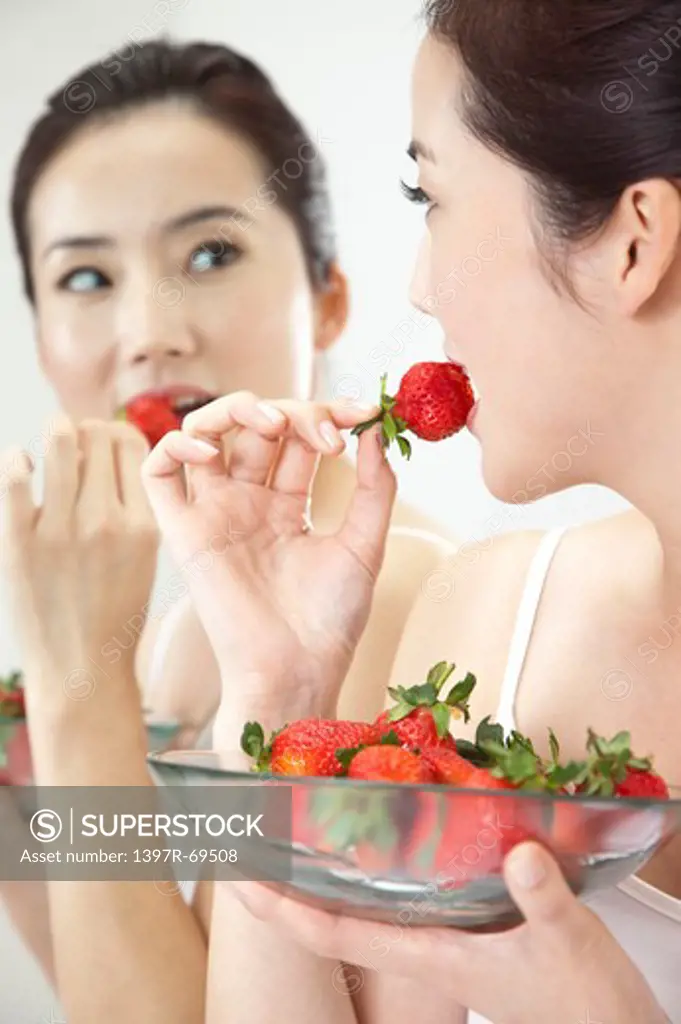 Beauty Treatment, Woman looking into mirror and eating a plate of strawberry