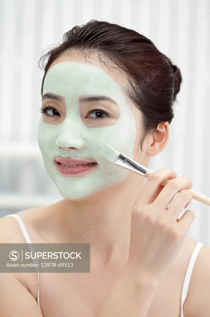 Beauty Treatment, Woman applying facial mask on face with a make-up brush