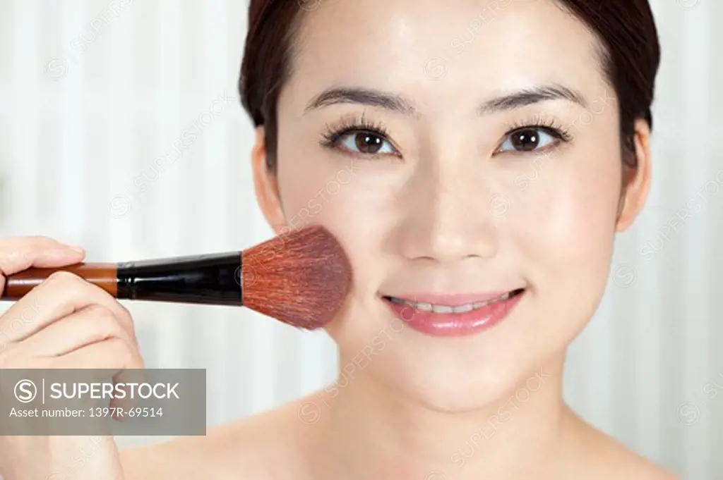 Beauty Treatment, Close-up of woman holding a blush brush on her face with smile