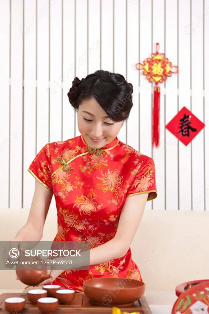 New Year, Young woman wearing Chinese traditional clothing and making tea ceremony with smile