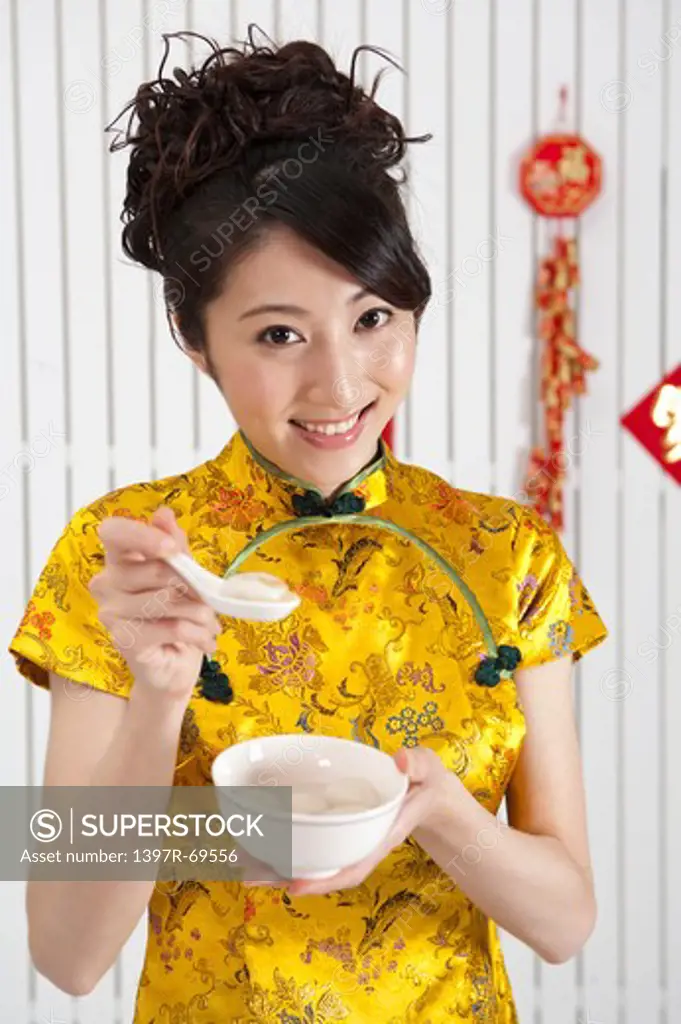 New Year, Young woman wearing Chinese traditional clothing and holding a bowl of stuffed dumplings with smile