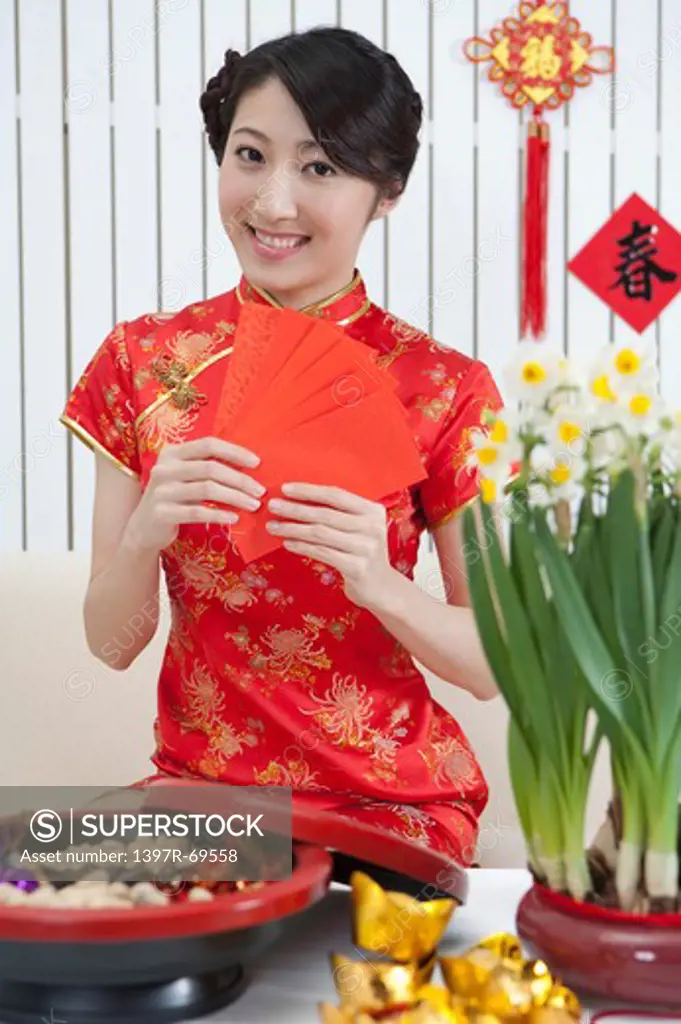 Young woman wearing Chinese traditional clothing and holding red envelopes with smile