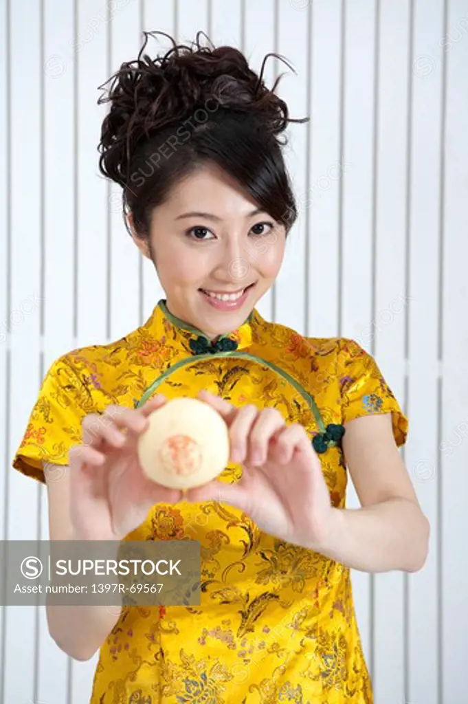 New Year, Young woman wearing Chinese traditional clothing and holding the snack with smile