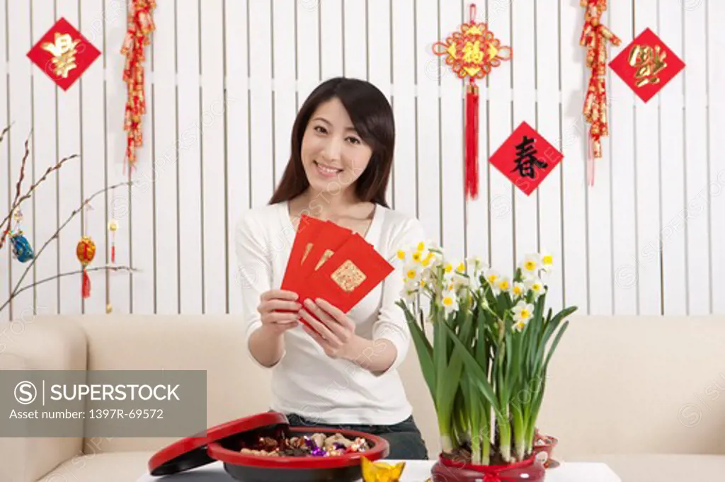 New Year, Young woman holding red envelopes and smiling at the camera