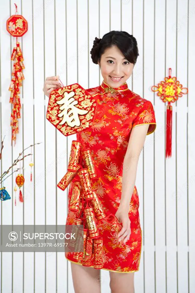 New Year, Young woman wearing Chinese traditional clothing and holding firecrackers with smile
