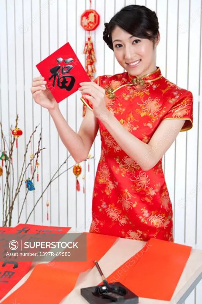 New Year, Young woman wearing Chinese traditional clothing and holding Chinese script with smile