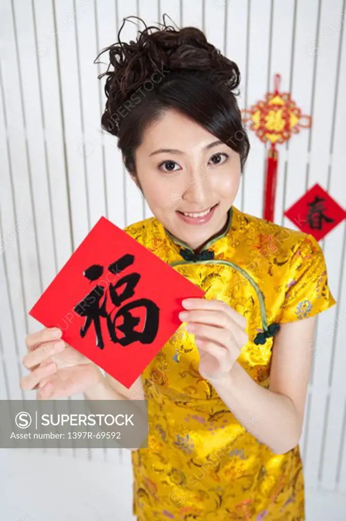 New Year, Young woman wearing Chinese traditional clothing and holding Chinese script with smile