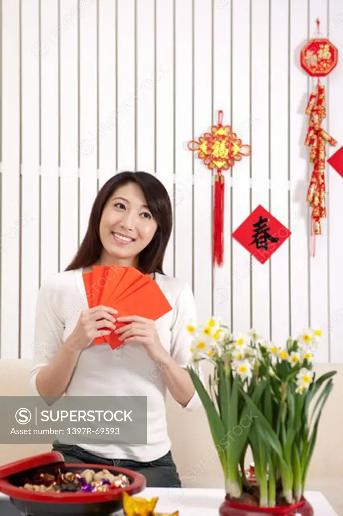 New Year, Young woman holding red envelopes and looking away with smile