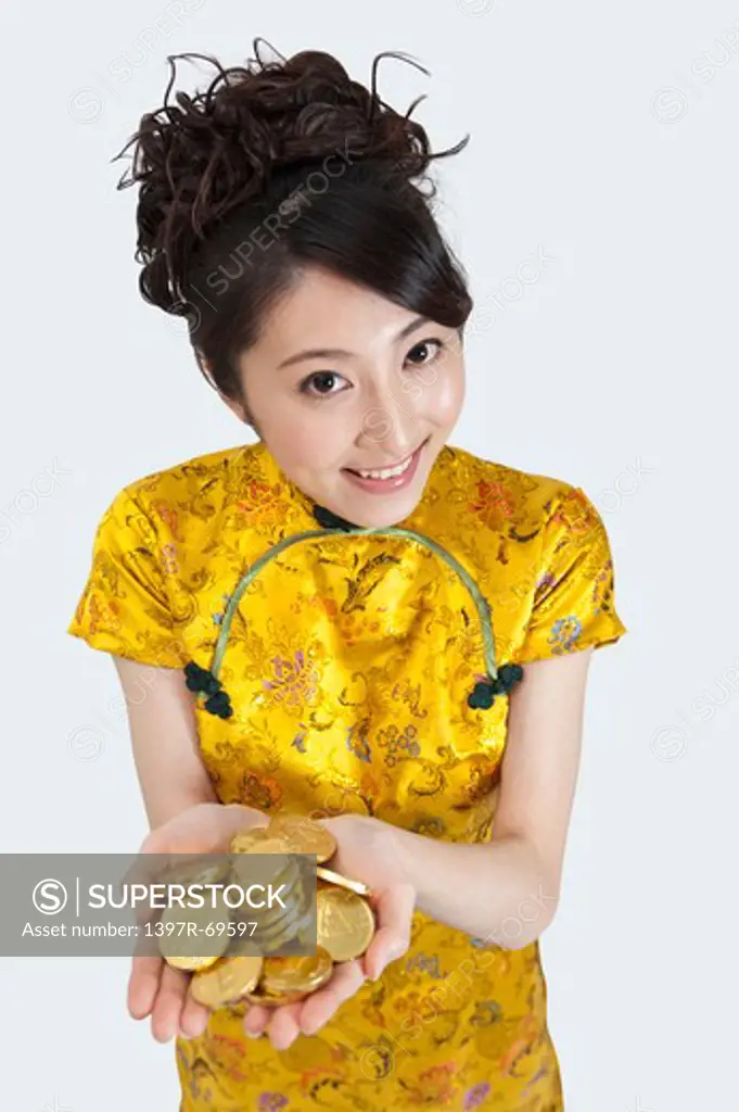 New Year, Young woman wearing Chinese traditional clothing and holding a stack of gold coins with smile