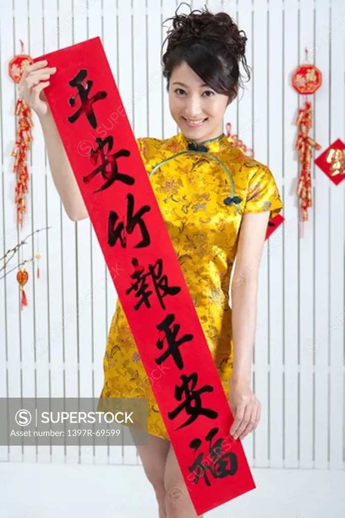 New Year, Young woman wearing Chinese traditional clothing and holding couplet with smile