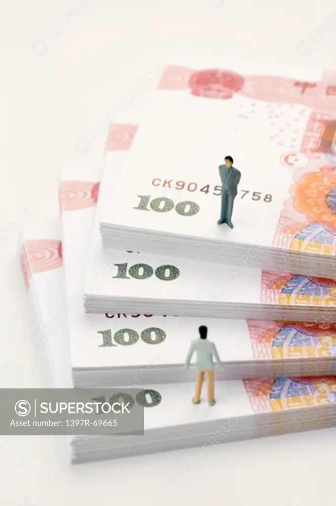 China Currency, two figurine men standing on top of stacks of paper money