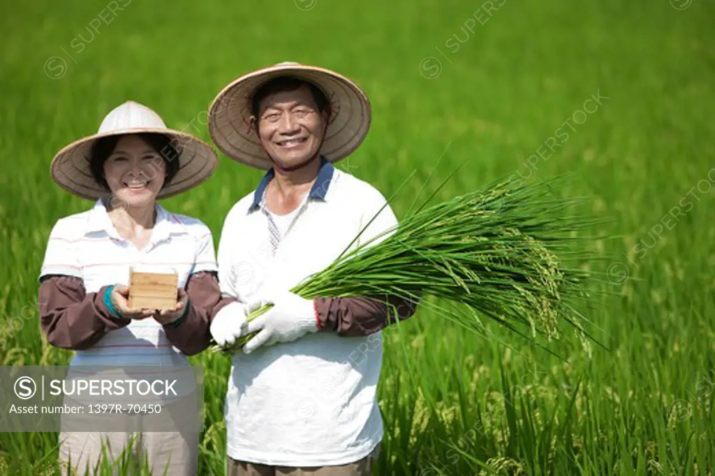 Famer couple standing in rice field, smiling