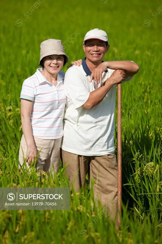 Farmer couple standing in rice field, smiling
